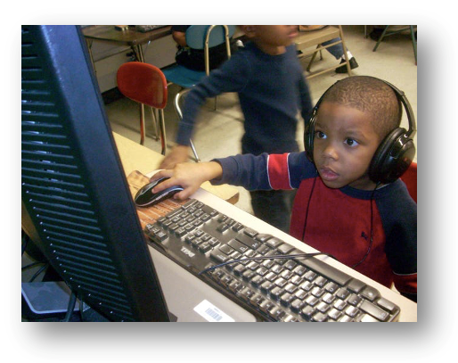 Photo of a boy sitting at a computer with his hand on the mouse