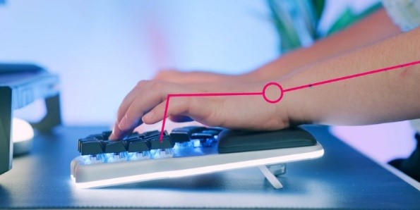 Photo of a keyboard with feet and a wrist rest in the front, with a person's hands positioned straighter over the top