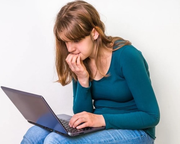 Picture of woman slouching looking at laptop on her knees